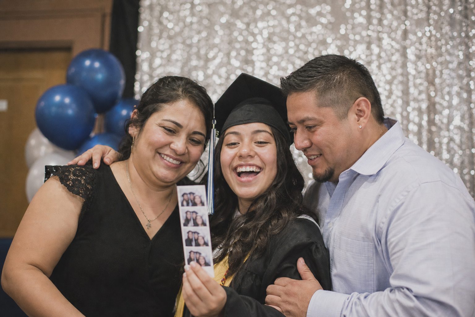 A graduate and family holding up a printed photo strip