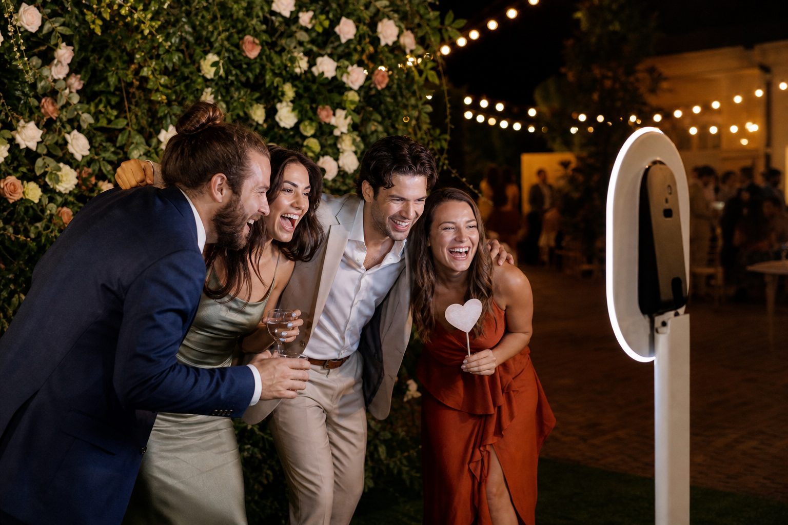 Wedding guests laughing together in an open-air photo booth